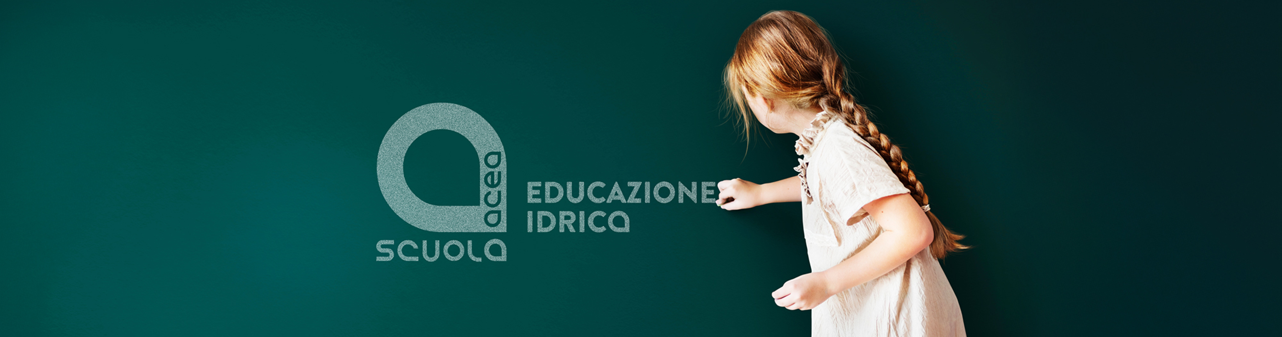 A little girl draws the logo of her school with chalk on the blackboard