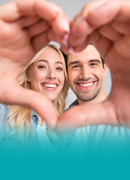 Un uomo e una donna, sorridenti, guardano l'obiettivo creando la forma di un cuore con le loro mani