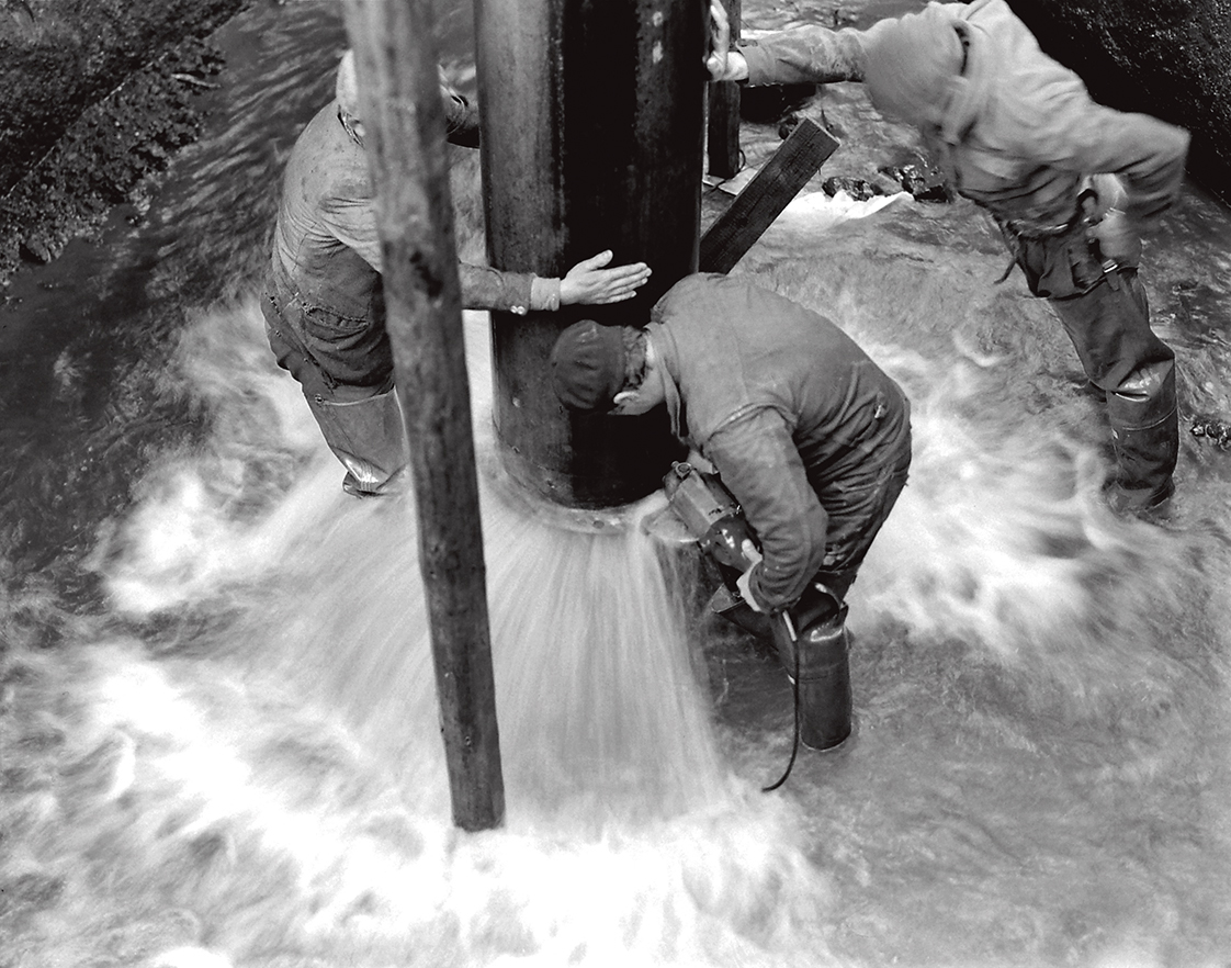 black-and-white photos of workers working in the aqueduct full of water