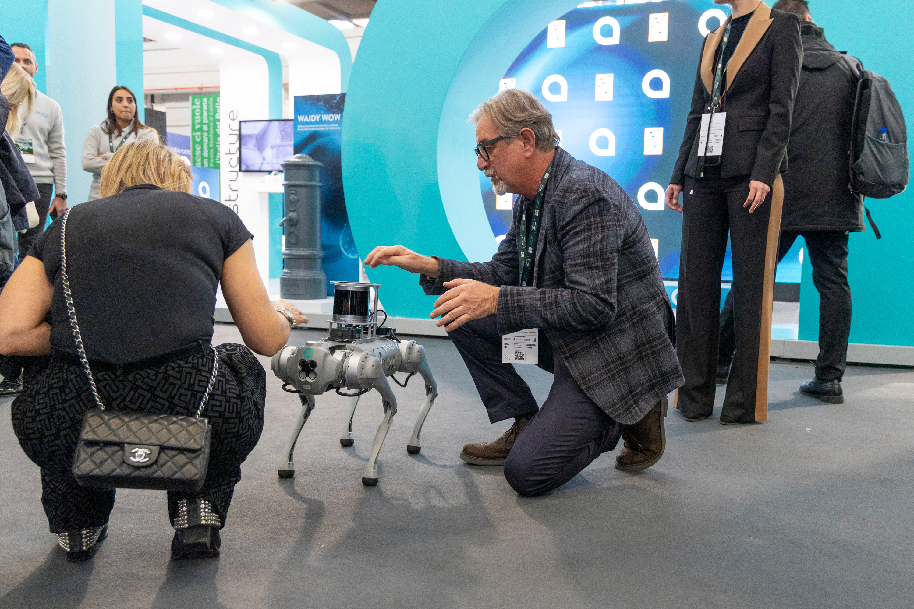 two kneeling people interacting with the dog-shaped acea robot