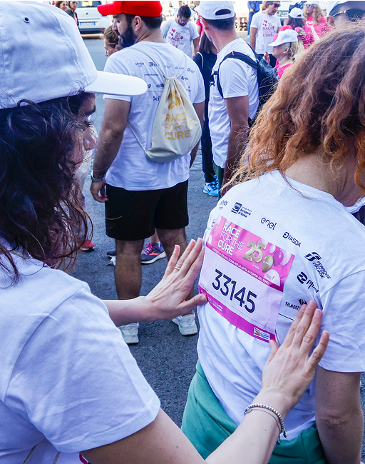A woman applies the adhesive with the competitor number to another woman during the Run for the Cure marathon.