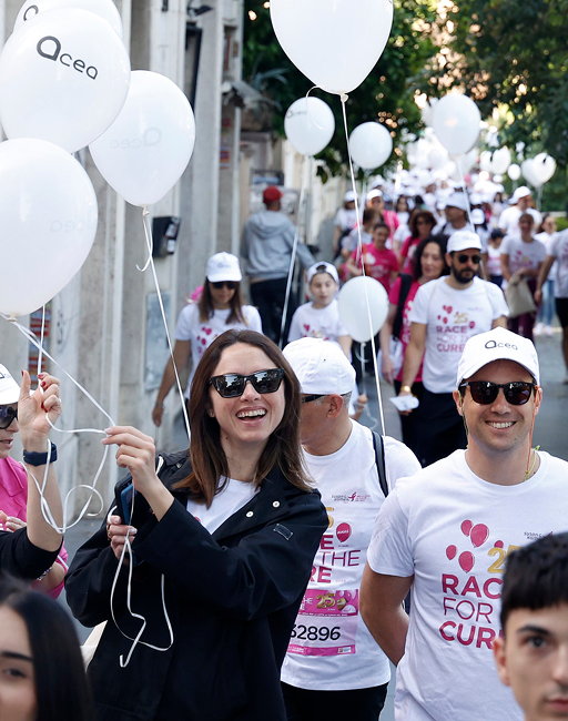 Woman wearing dark sunglasses smiles at the camera while holding a balloon with the Acea logo.