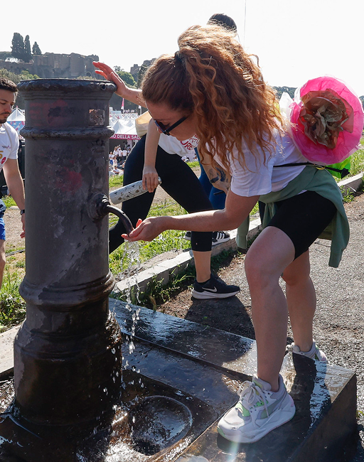 Woman quenches her thirst at a public drinking fountain during the Acea Run for the Cure event.