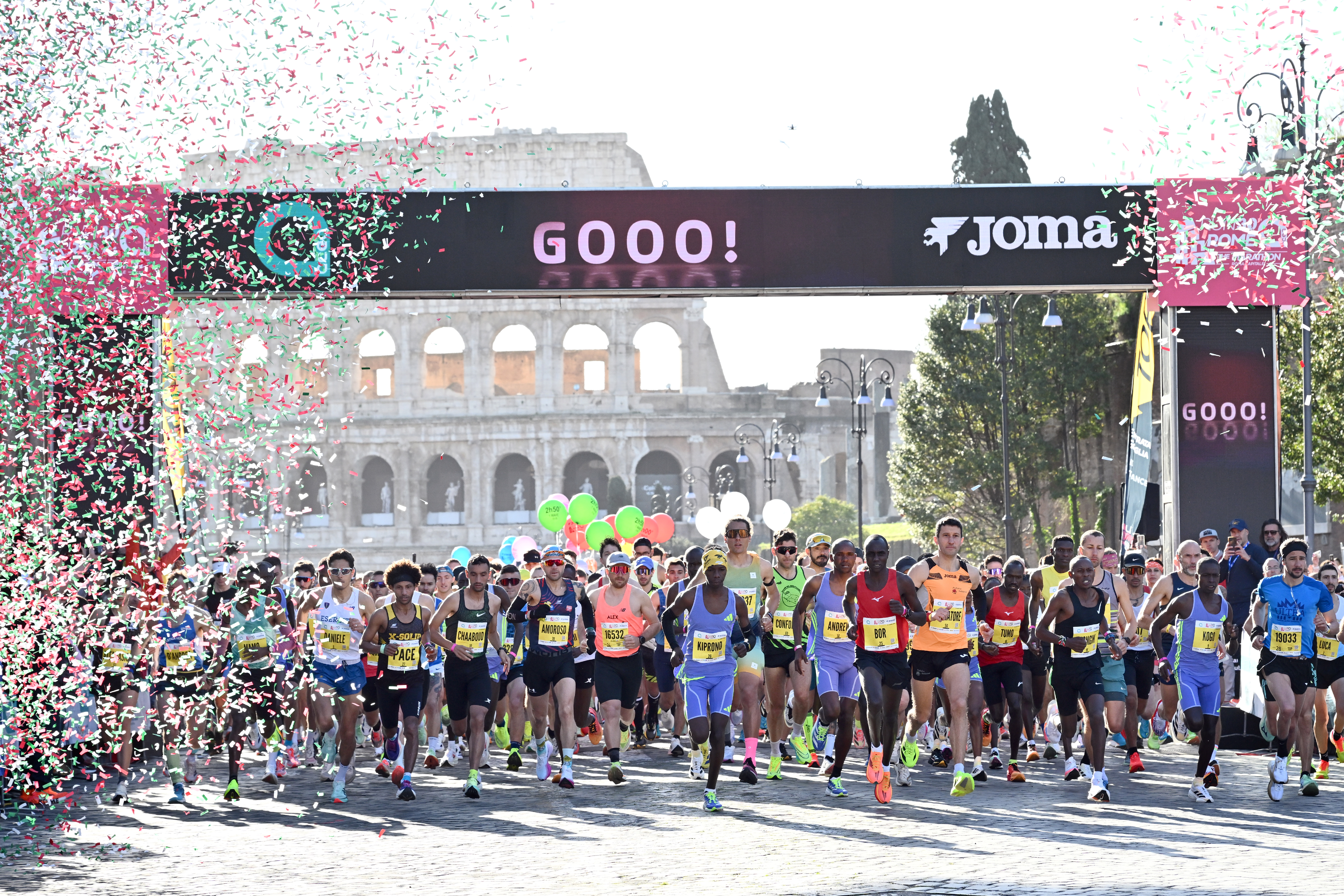 The winners as they cross the finish line, the other runners following. There are also the exploded confetti