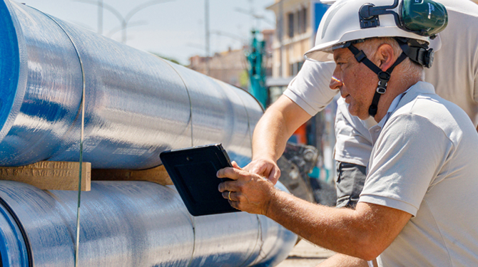 Un operatore ispeziona delle tubature con un tablet
